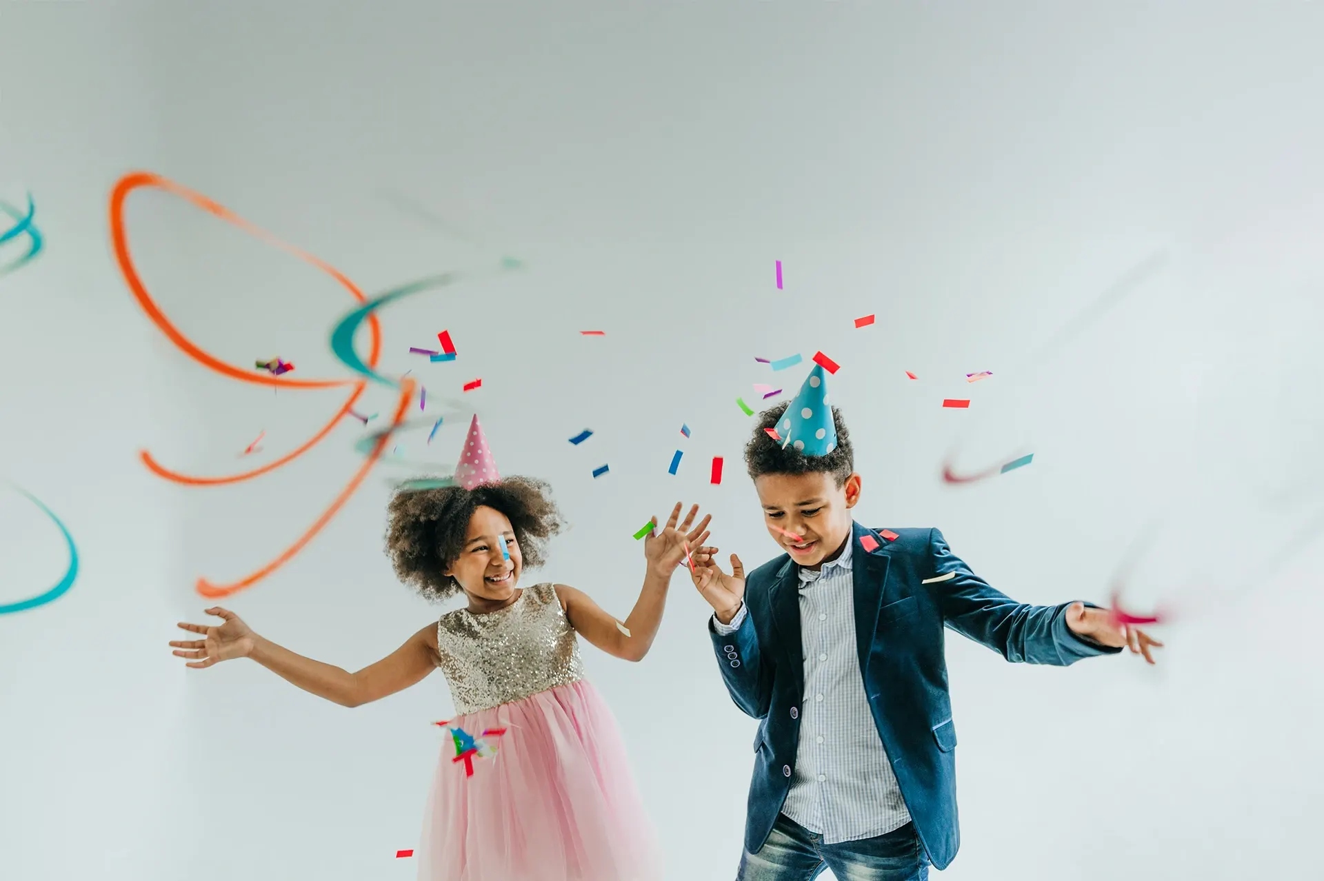 Zwei Kinder mit Partyhüten tanzen fröhlich